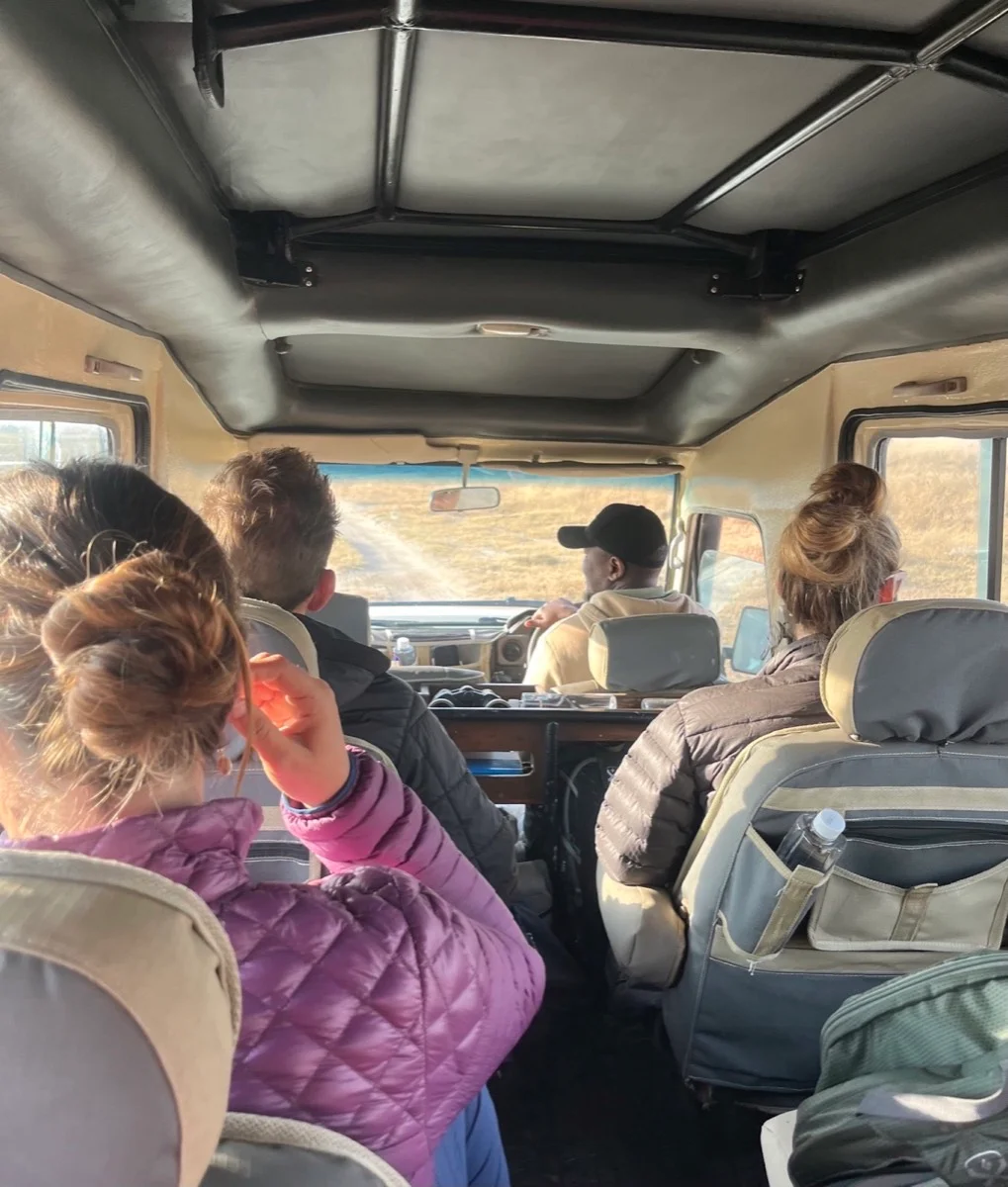 Travelers and their driver-guide journeying through Tanzania in a safari vehicle