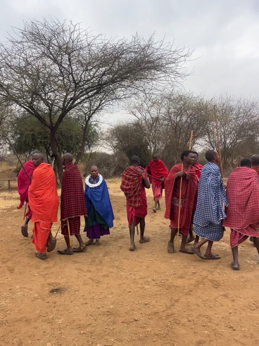 Maasai community members gathered outdoors in colorful traditional shúkà clothing