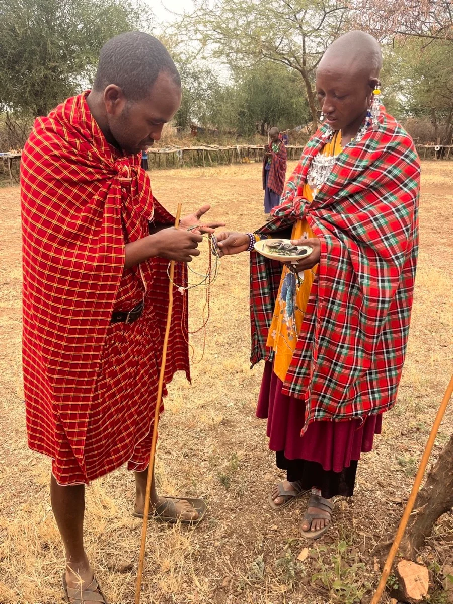 Two Maasai community members sharing handmade beadwork in Tanzania