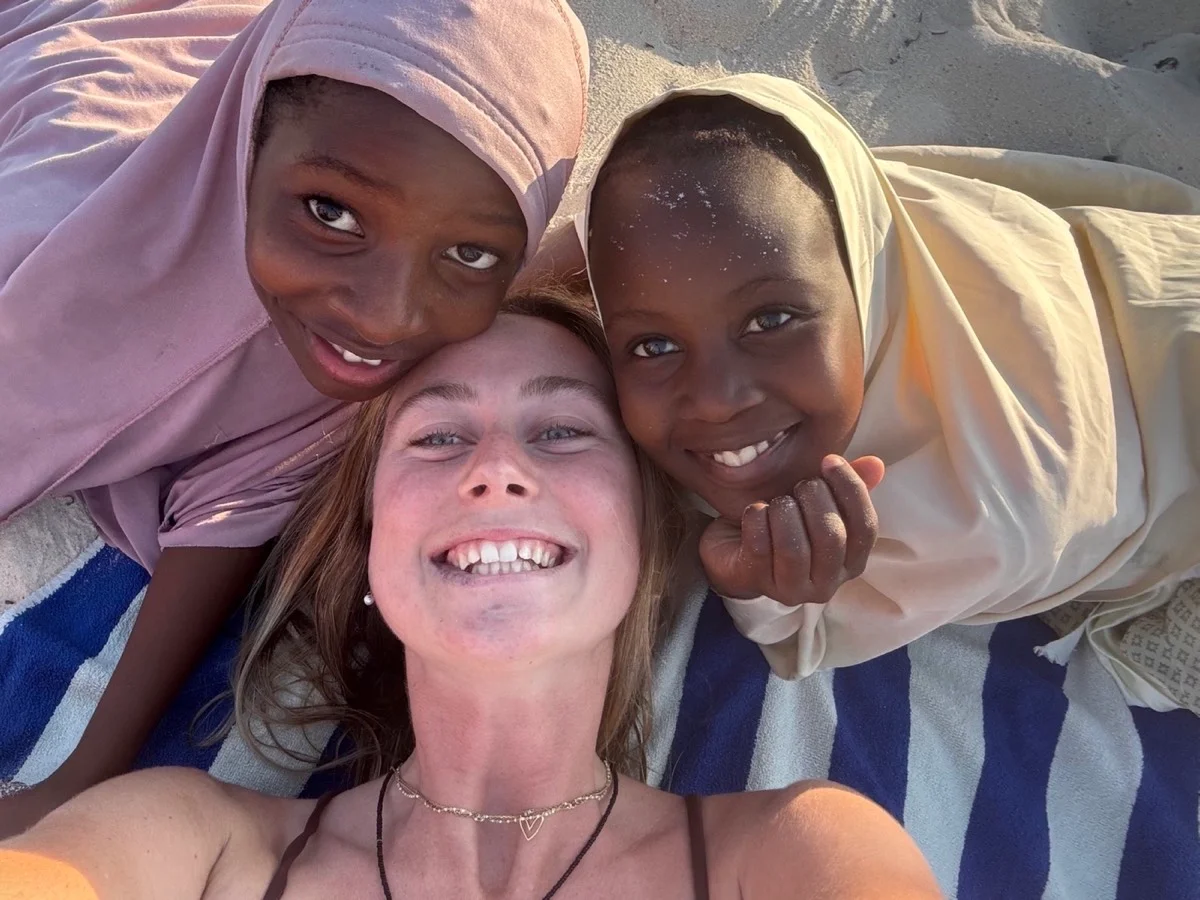 A traveler and two smiling Zanzibari girls sharing a joyful moment on the beach