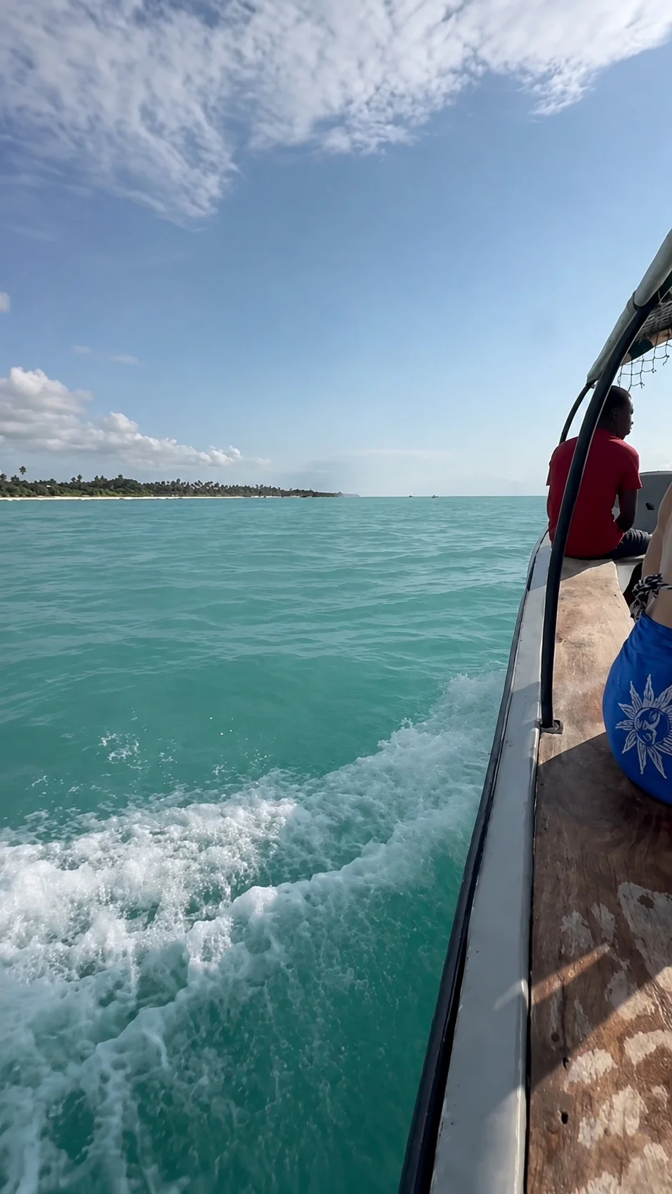 A small motorboat crossing turquoise water along the Zanzibar coast