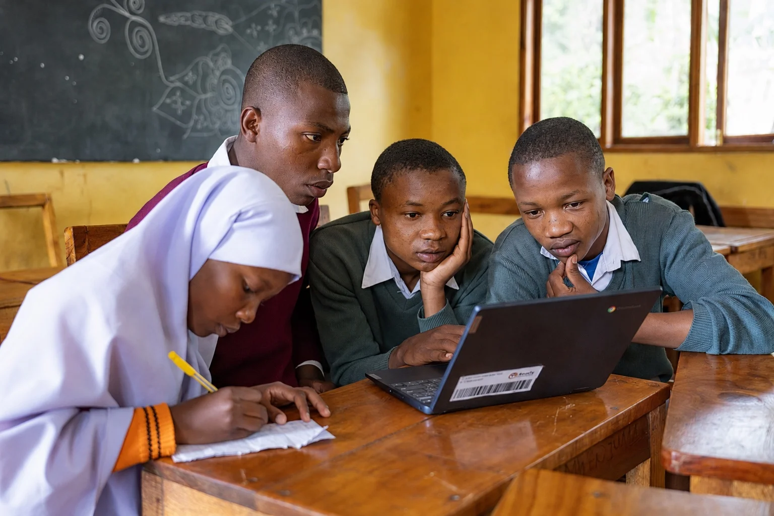 Tanzanian students learning together with a computer in their classroom