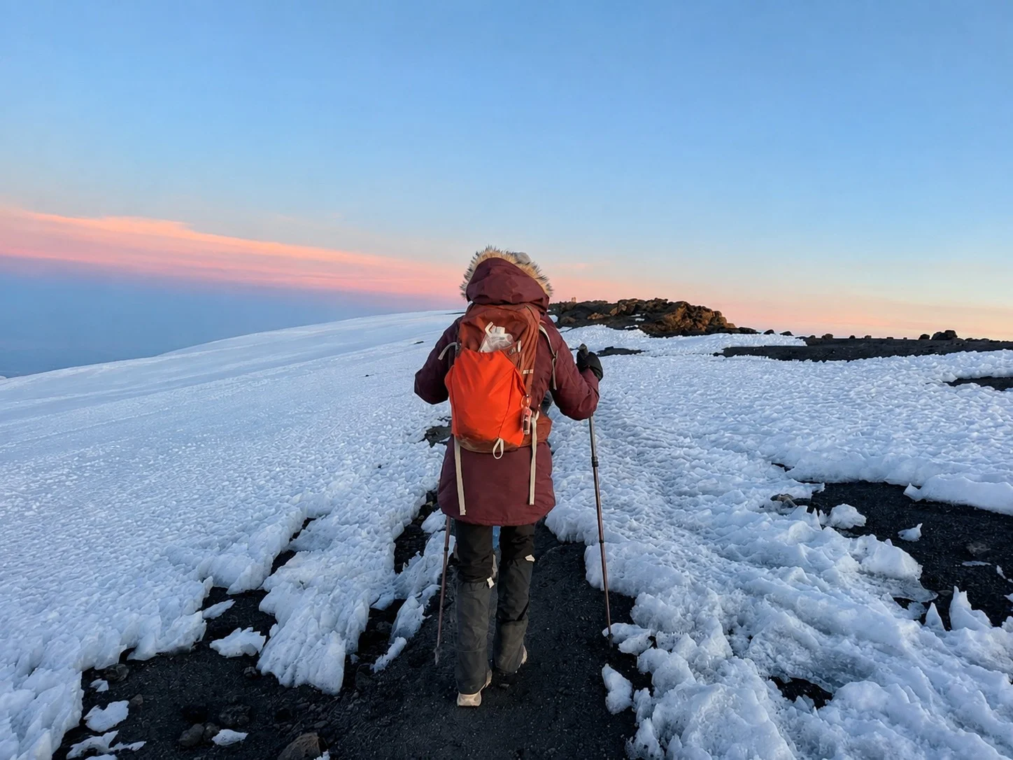 A climber using trekking poles across Kilimanjaro’s snow-covered upper slopes