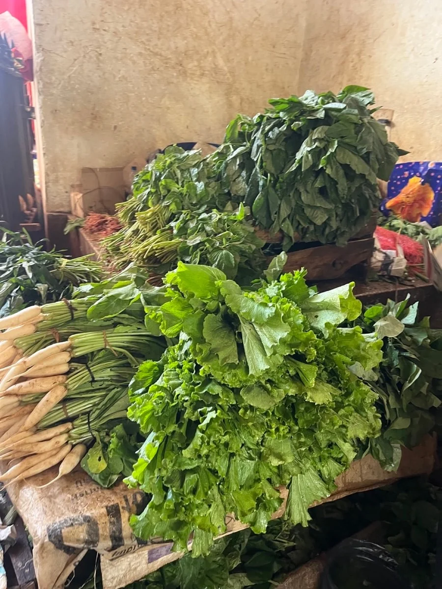 Bundles of fresh leafy greens and roots at a Zanzibar market