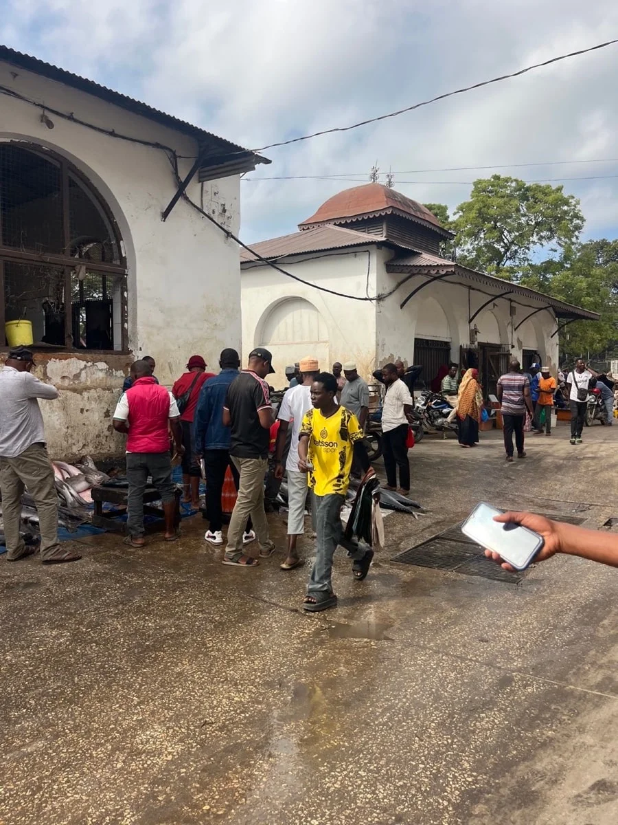 A busy courtyard outside a historic arched market building in Zanzibar