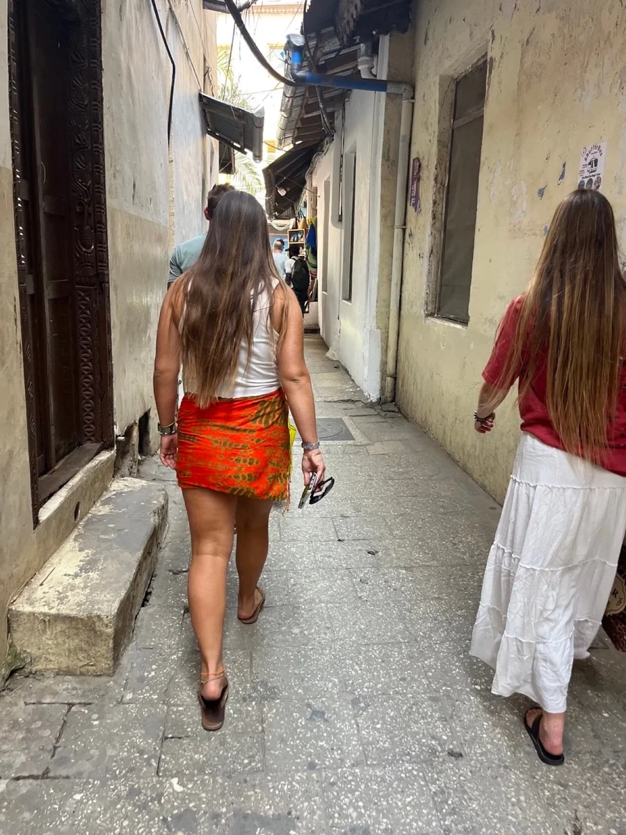 Two travelers walking through a narrow Stone Town lane