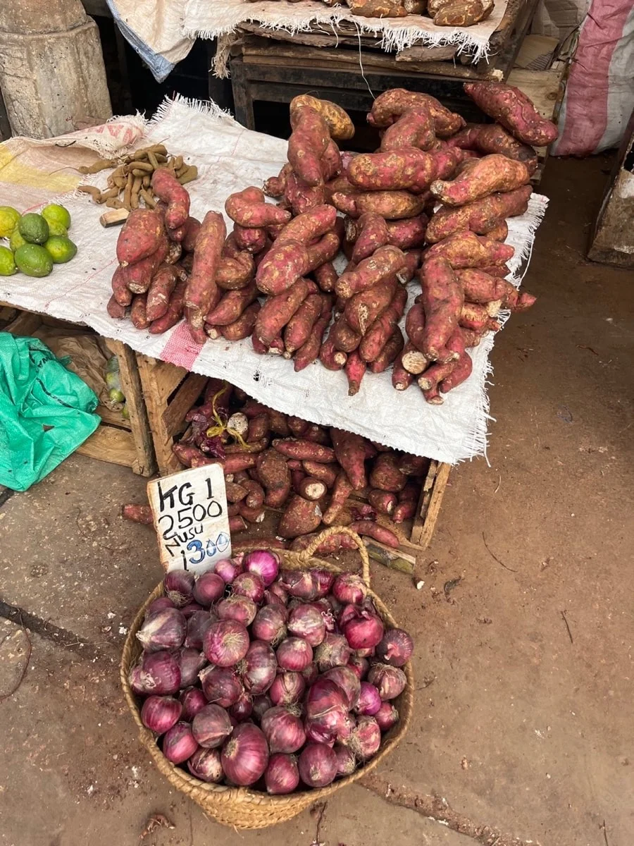 Red sweet potatoes and onions displayed in baskets at a Zanzibar market